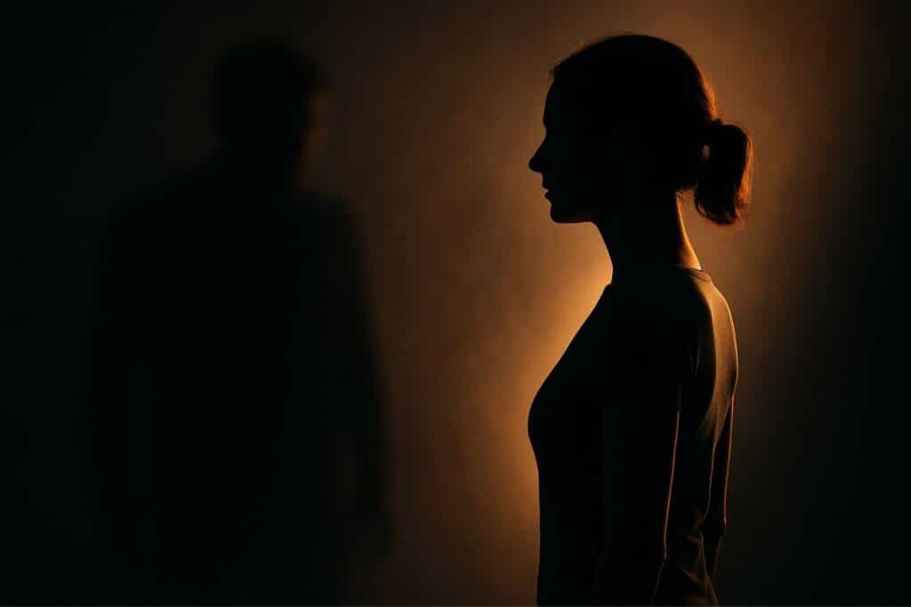 femme faisant face à une ombre menaçante, métaphore de l’affrontement psychologique