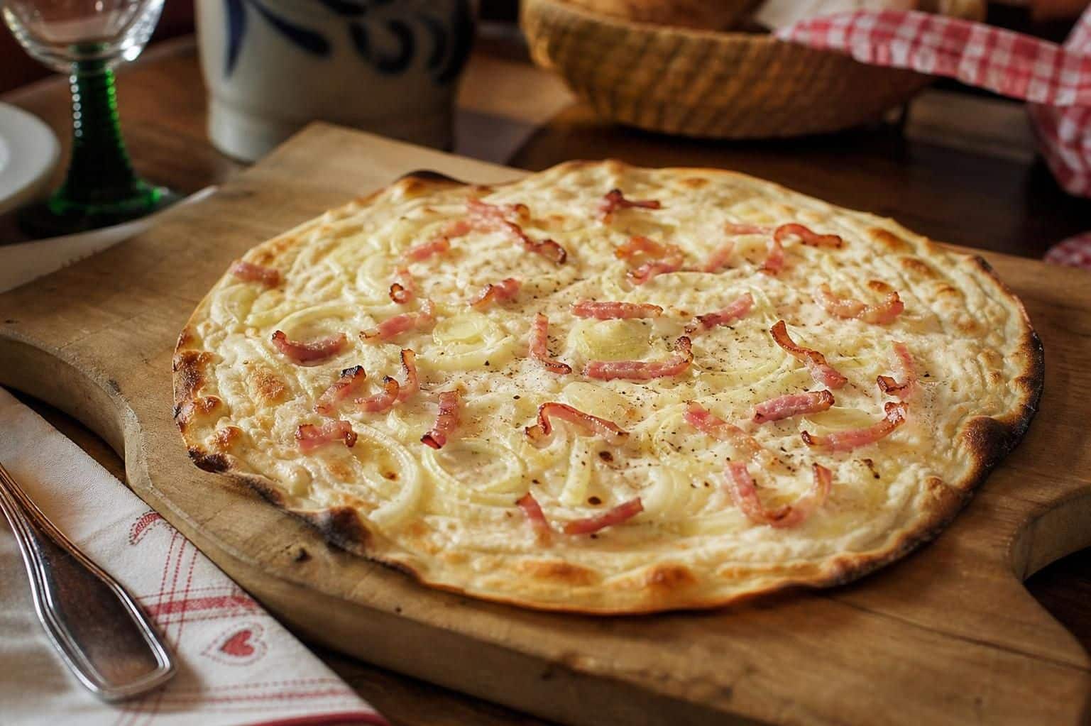 découvrez notre recette authentique de flammekueche alsacienne, une délicieuse tarte fine garnie de crème, oignons et lardons, parfaite pour un repas convivial.